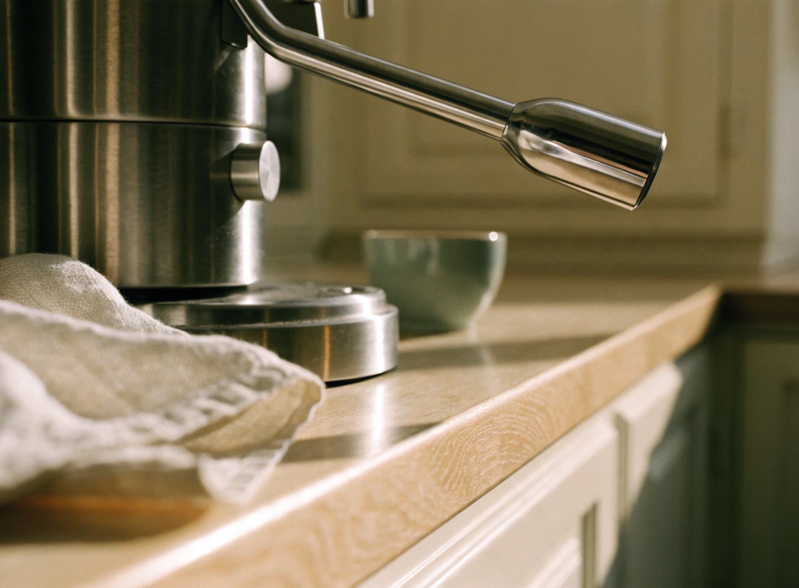 Close detail of a stainless espresso machine on an oak worktop